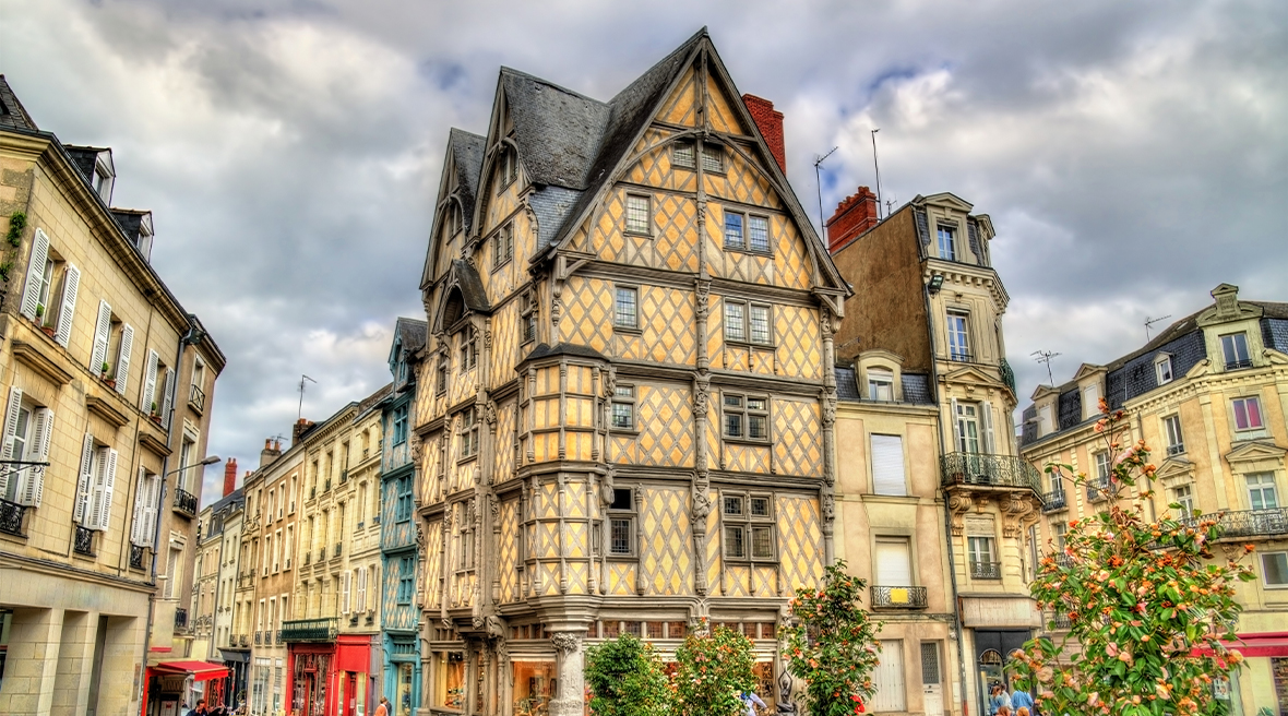 A quirky six-storey half-timbered medieval building on the edge of a square, with less attractive buildings around it
